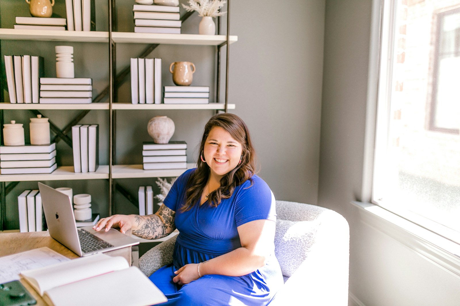 Friendly advisor smiling at her desk with laptop and notebook
