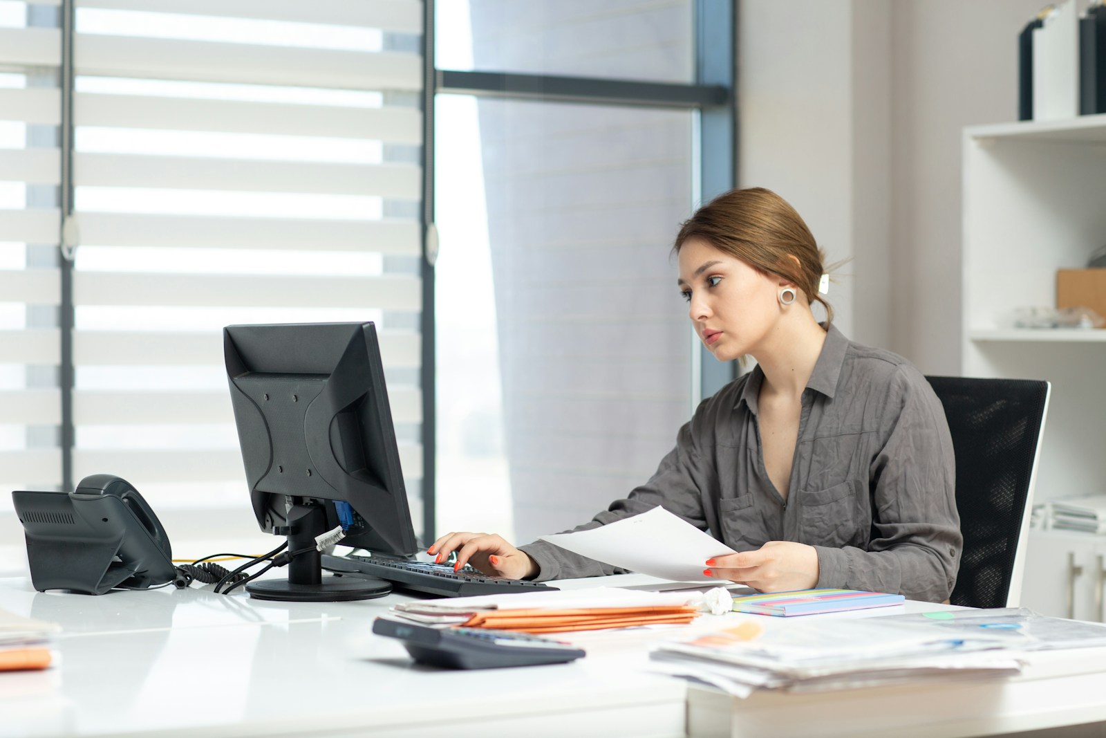 Bookkeeper reconciling records at a bright office desk
