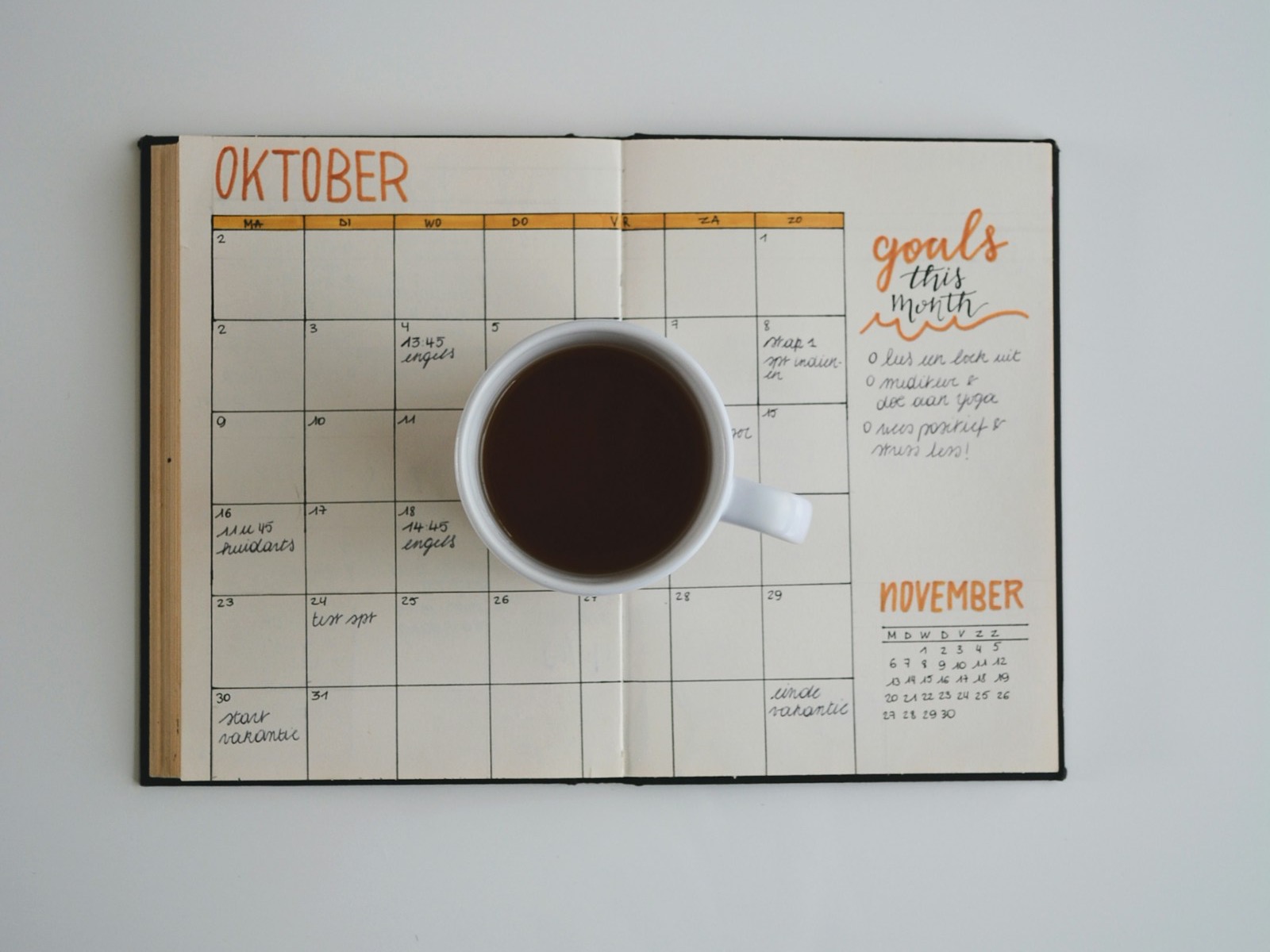 Monthly planner spread with a cup of coffee marking key dates